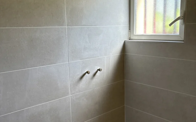 Faïence murale posée dans un espace douche à Liffré avec raccordements de plomberie visibles.