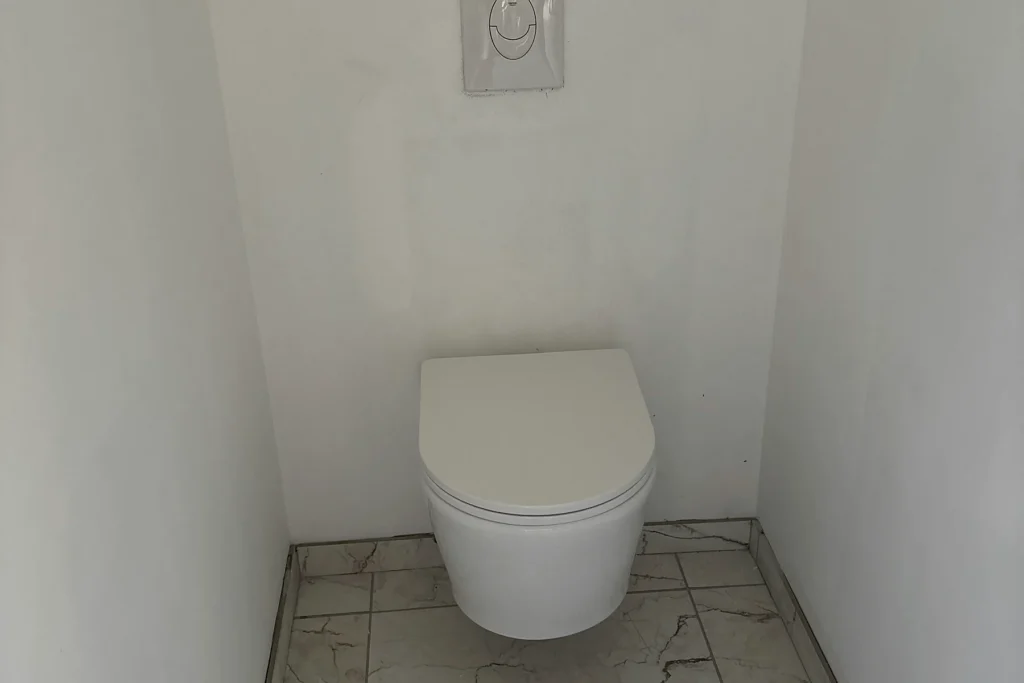 WC suspendu avec bâti-support habillé et carrelage effet marbre dans une salle de bains neuve.