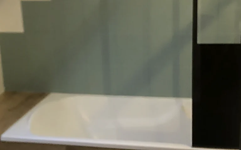 Salle de bains mansardée rénovée à Châteaubourg avec baignoire habillée et verrière noire