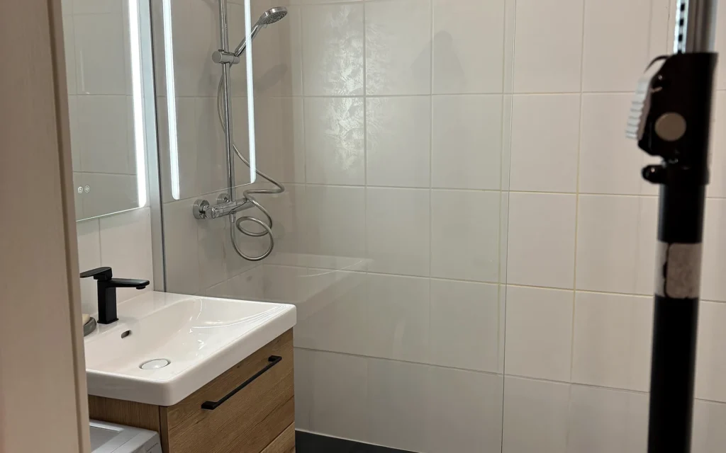 Salle de bains rénovée à Châteaubourg avec douche vitrée et meuble vasque bois.
