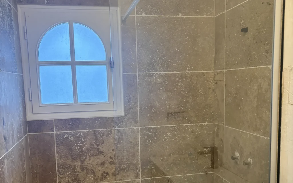 Salle de bains après rénovation à Combourtillé avec receveur blanc et nouvelle faïence murale.