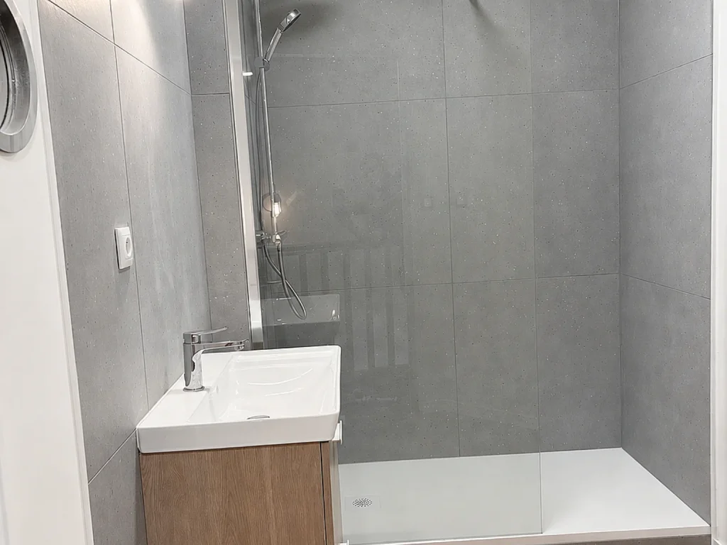 Salle de bains rénovée avec douche ouverte et meuble vasque en bois