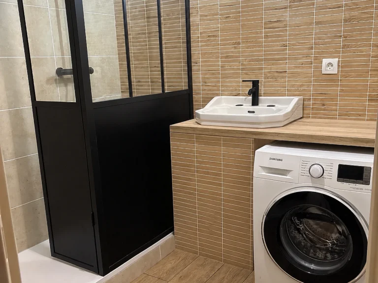 Salle de bains rénovée avec douche vitrée, meuble vasque et espace buanderie